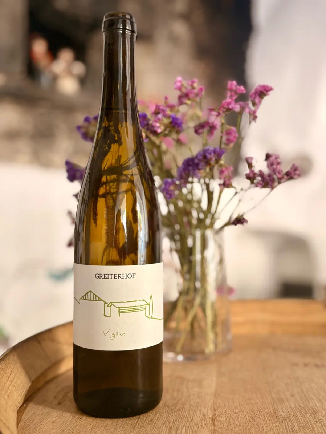Flasche des Weißweins Vigilius vom Greiterhof auf einem Holztisch mit Trockenblumen